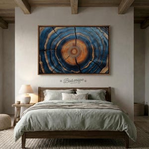May include: A framed artwork depicting a cross-section of a tree trunk, showcasing concentric rings in shades of blue and orange. The artwork is mounted above a bed with light green bedding. The artwork is approximately 48 inches wide.