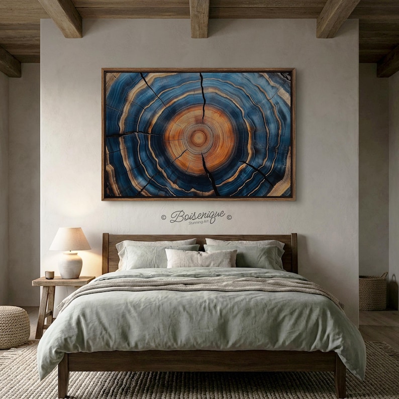 May include: A framed artwork depicting a cross-section of a tree trunk, showcasing concentric rings in shades of blue and orange. The artwork is mounted above a bed with light green bedding. The artwork is approximately 48 inches wide.
