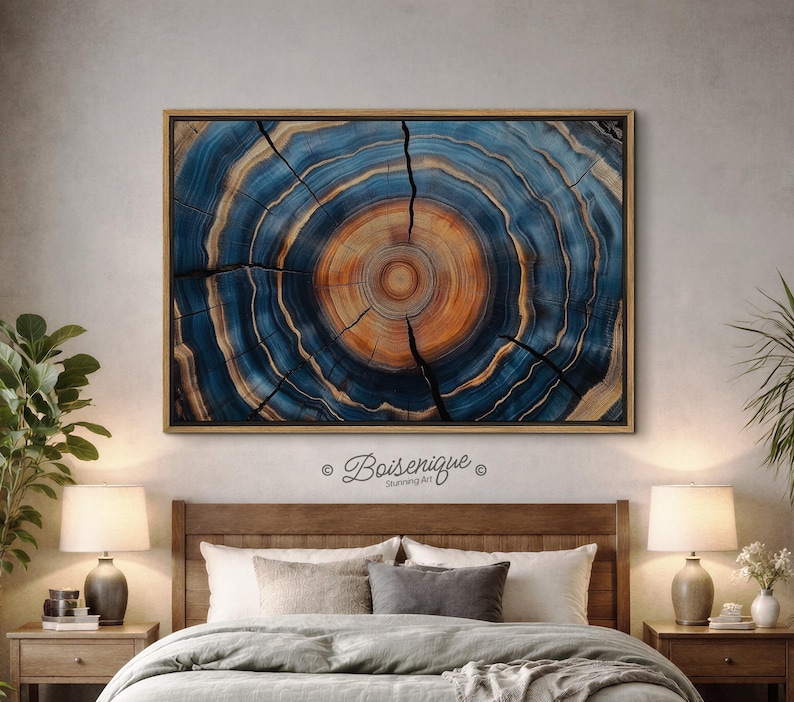 May include: A framed artwork featuring a cross-section of a tree trunk, showcasing concentric rings in shades of blue, orange, and tan. The artwork is rectangular and mounted in a wooden frame. The text "Boisenique Stunning Art" is in the lower right corner.