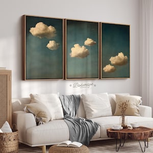 Puede incluir: Un conjunto de tres impresiones enmarcadas que presentan nubes abstractas sobre un fondo azul oscuro. Las impresiones están en marcos de madera y están colgadas en una pared blanca.