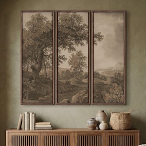 May include: Triptych of sepia-toned landscape art prints in dark brown frames. The artwork depicts trees, rocks, and a river, creating a serene, natural scene. The prints are displayed above a wooden cabinet with decorative items.