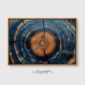 May include: A framed art print featuring a cross-section of a tree trunk. The artwork showcases concentric rings in shades of blue, orange, and brown, with natural cracks. The frame is a light brown color. The text "Boisenique Stunning Art" is in the bottom right corner.