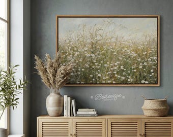May include: A framed canvas art print depicting a field of white wildflowers and tall grasses. The artwork is displayed above a wooden cabinet with a vase of dried plants, books, and a woven basket. The text "Boisenique" is visible.