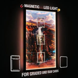 Pode incluir: Uma moldura retangular preta com luz LED magnética para cartões graduados e brutos. A moldura apresenta um gráfico de paisagem de cânion retroiluminado com três ranhuras verticais. O texto diz MAGNETIC LED LIGHT e FOR GRADED AND RAW CARDS.