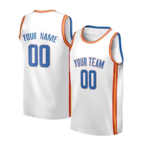 Op de afbeelding: Twee witte basketbalshirts. Eén shirt heeft "YOUR NAME" en het nummer "00" in blauw op de rug. Het andere shirt heeft "YOUR TEAM" en het nummer "00" in blauw op de voorkant. Beide shirts hebben oranje en rode accenten.