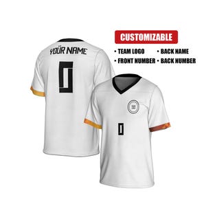 Op de afbeelding: Wit, aanpasbaar sportshirt met zwarte details. Voorzien van een zwarte V-hals, zwart nummer 0 en een teamlogo. De achterkant van het shirt heeft de tekst "YOUR NAME". Aanpasbaar met teamlogo, achternaam en voor- en rugnummers.