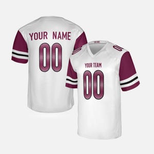 Puede incluir: Camiseta de fútbol blanca con mangas y detalles granate. Presenta el número "00" en granate con un diseño de malla, y los textos "YOUR NAME" y "YOUR TEAM". Incluye rayas negras en las mangas.