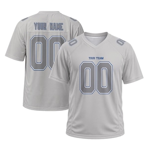 May include: A light gray short-sleeved sports jersey with a V-neck collar. The front features the text "YOUR TEAM" above the number "00" in gray with blue outlines. The back displays "YOUR NAME" above the number "00" in the same color scheme.