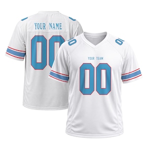 Puede incluir: Una camiseta deportiva blanca con números 00 en azul claro con bordes rojos en la parte delantera y trasera. El frente muestra el texto YOUR TEAM, mientras que la parte posterior indica YOUR NAME. Las mangas tienen rayas azul claro y rojas, y los hombros presentan números 00 en azul claro.