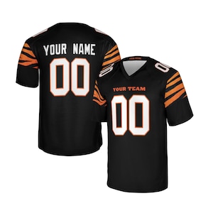 May include: A black jersey with orange tiger stripes on the sleeves, featuring the text YOUR NAME and the number 00 on the back, and the text YOUR TEAM and the number 00 on the front. The jersey has a V-neck collar and short sleeves.