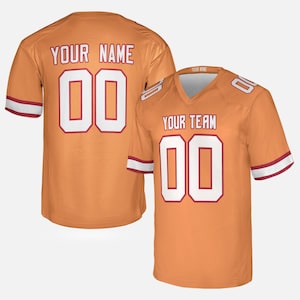 May include: An orange jersey with white and red trim, featuring the text YOUR NAME and the number 00 on the back, and the text YOUR TEAM and the number 00 on the front. The V-neck shirt includes white and red stripes on the short sleeves.