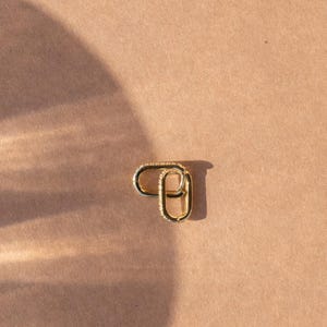 May include: A pair of gold oval hoop earrings with a textured surface.