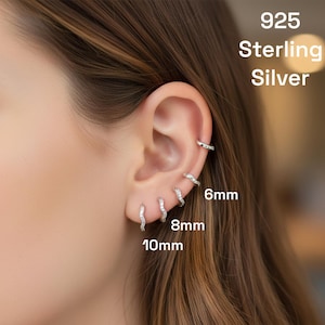 Op de afbeelding: Sterling zilveren oorbellen in verschillende maten worden op een oor getoond. De oorbellen hebben een diameter van 6 mm, 8 mm en 10 mm. De tekst "925 Sterling Silver" is zichtbaar.