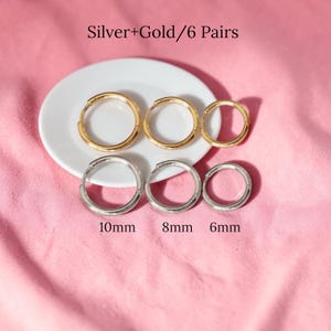 May include: Six pairs of hoop earrings in gold and silver tones are displayed on a white plate against a pink background. The earrings vary in size, with measurements of 10mm, 8mm, and 6mm. The text "Silver+Gold/6 Pairs" is at the top.