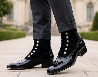 May include: A pair of black ankle boots featuring a glossy patent leather toe cap with brogue detailing and a matte black shaft. The boots are accented with a vertical row of silver-toned buttons along the front and are paired with grey trousers.