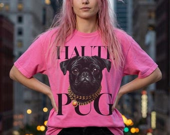 May include: A bright pink short-sleeved t-shirt featuring a graphic of a black pug wearing a thick gold chain necklace with a circular pendant. The text "HALT" is printed above the pug, and the letters "P G" are printed below the dog's chin.
