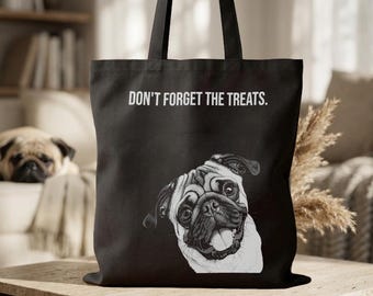 May include: A black tote bag featuring a white line-art illustration of a pug dog with its tongue out. The text DON'T FORGET THE TREATS. is printed in white capital letters above the dog illustration. The bag has two black shoulder straps.