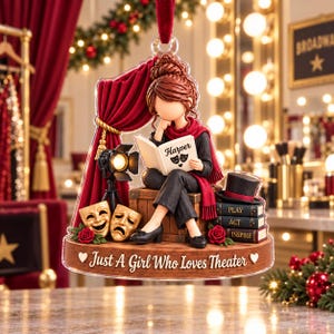 May include: A decorative hanging ornament featuring a figure sitting on a wooden crate, reading a book labeled Harper with theater masks. It includes red curtains, a spotlight, gold comedy and tragedy masks, books, and the text Just A Girl Who Loves Theater.
