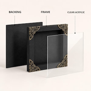 May include: A square black frame with ornate gold-toned metal corner accents, shown in an exploded view with a separate black backing panel and a clear acrylic sheet. The components are labelled with the text BACKING, FRAME, and CLEAR ACRYLIC.