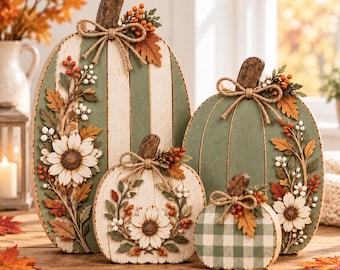 May include: A set of four decorative wooden pumpkins in varying sizes, featuring sage green and cream stripes or gingham patterns. Each pumpkin is adorned with a dark wood stem, a jute twine bow, white floral accents, and orange berries.