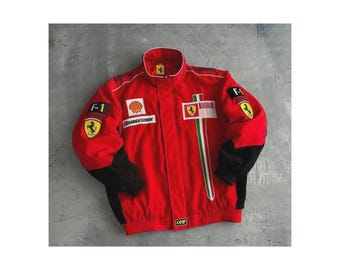 May include: A red Ferrari racing jacket with black sleeves and white accents. The jacket features multiple patches, including the Ferrari logo, Bridgestone, and F-1. The jacket has a stand-up collar and a zipper closure.