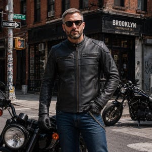 May include: A black leather motorcycle jacket featuring a mandarin collar, a full-length front zip, two horizontal zipped chest pockets, and two lower side pockets. The jacket has long sleeves with reinforced shoulder panels and a smooth finish.