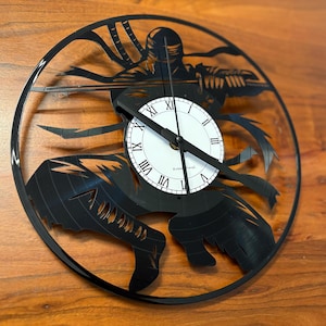 Op de afbeelding: Zwarte vinyl platen klok met een silhouet van een ninja die een zwaard vasthoudt. De wijzerplaat van de klok is wit met zwarte Romeinse cijfers.