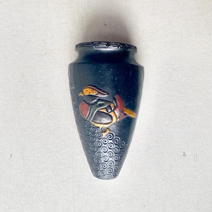 May include: A dark blue vase with a detailed bird design in shades of red, yellow, and green. The vase has a textured, swirling pattern on the lower half and a decorative rim.
