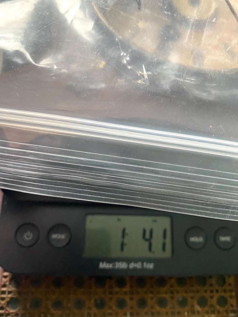 Puede incluir: Una b&aacute;scula digital muestra un peso de 14,1 onzas. La b&aacute;scula negra tiene varios botones y una pantalla digital. Una bolsa de pl&aacute;stico transparente que contiene finas varillas de metal plateado est&aacute; encima de la b&aacute;scula.