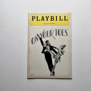 May include: A vintage Playbill from the Virginia Theatre, featuring the title "On Your Toes." The cover has a yellow banner with the word "PLAYBILL" in bold black letters. The image shows a black and white illustration of a male and female dancer.
