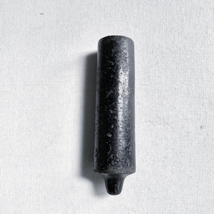 May include: A dark, cylindrical object with a textured surface and a rounded base. The object is black and appears to be made of metal. The item is set against a white background.