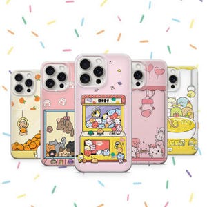 May include: Five different phone cases with various designs. The cases are all clear and have a white border. The designs include a claw machine with cartoon animals, a cat with a crown, a cat with a heart, a cat with a crown, and a cat with a heart. The cases are all for iPhone 13 Pro.