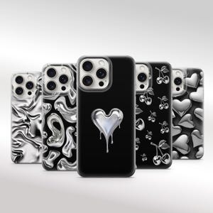 May include: A collection of five phone cases with various designs. The cases feature a mix of black and silver colors. Designs include a melting heart, abstract patterns, cherries, and hearts. The cases are shown against a white background.