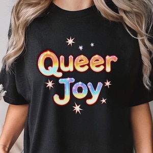 Camiseta com letras bolha Queer Joy – Camiseta com brilho e arco-íris, estampa LGBTQ, camiseta colorida e divertida para comemoração queer, visual com efeito glitter