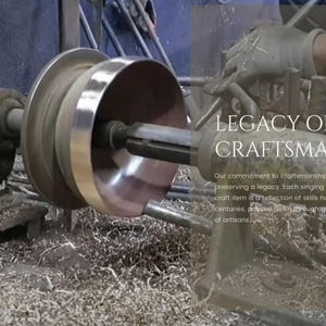 K&ouml;nnte beinhalten: Nahaufnahme eines Metall-Singbeh&auml;lters, der auf einer Drehbank geformt wird. Die Schale wird von einem Metallstab gedreht, und auf dem Boden liegen Metallsp&auml;ne. Der Text "LEGACY OF CRAFTSMANSHIP" ist &uuml;ber das Bild gelegt. Unser Engagement f&uuml;r Handwerkskunst besteht darin, ein Verm&auml;chtnis zu bewahren. Jede Singenschale und jedes handwerkliche Produkt ist ein Spiegelbild von &uuml;ber Jahrhunderte hinweg verfeinerten F&auml;higkeiten, die &uuml;ber Generationen von Handwerkern weitergegeben wurden.