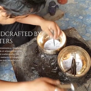 K&ouml;nnte beinhalten: Eine Person fertigt handwerklich ein Paar Metall-Sing-Schalen an. Die Schalen sind poliert und haben komplizierte Designs. Der Text "HANDCRAFTED BY MASTERS" ist auf dem Bild zu sehen. Jedes St&uuml;ck ist ein Meisterwerk, geformt von den geschickten H&auml;nden von Handwerkern, die sowohl Geschichte als auch Handwerkskunst ehren. Unser Engagement f&uuml;r Authentizit&auml;t bringt Ihnen Produkte, die sowohl sch&ouml;n als auch bedeutungsvoll sind.