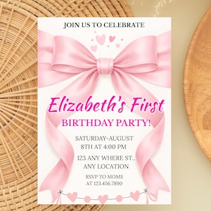 May include: A white invitation card with a pink bow and ribbon design. The text reads "Elizabeth's First Birthday Party!" with event details. The card is on a woven background.