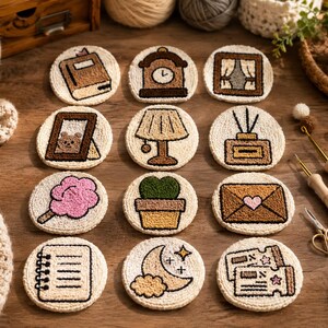 May include: A set of twelve circular tufted coasters featuring various embroidered designs including a book, clock, window, picture frame, lamp, diffuser, candy floss, potted plant, envelope, notebook, moon with stars, and two tickets.