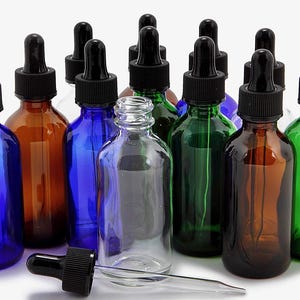 May include: A collection of ten glass dropper bottles in various colors, including blue, green, brown, and clear. The bottles have black dropper caps and are arranged on a white surface.