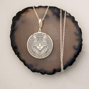 Gold-plated cat medallion necklace featuring a detailed feline with crescent moons, runes, and floral engravings, symbolizing intuition, independence, and mystical energy