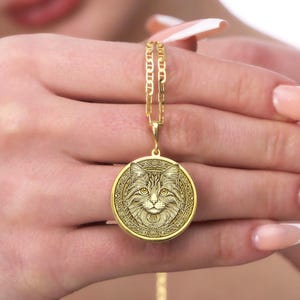 Gold-plated cat medallion necklace featuring a detailed feline with crescent moons, runes, and floral engravings, symbolizing intuition, independence, and mystical energy