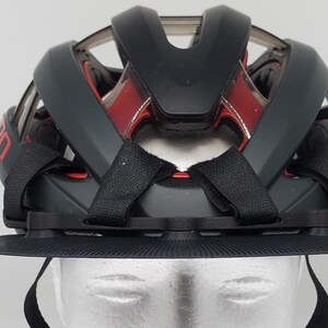 May include: Black bicycle helmet with a red and black design and a black visor. The helmet has adjustable straps and a chin strap.
