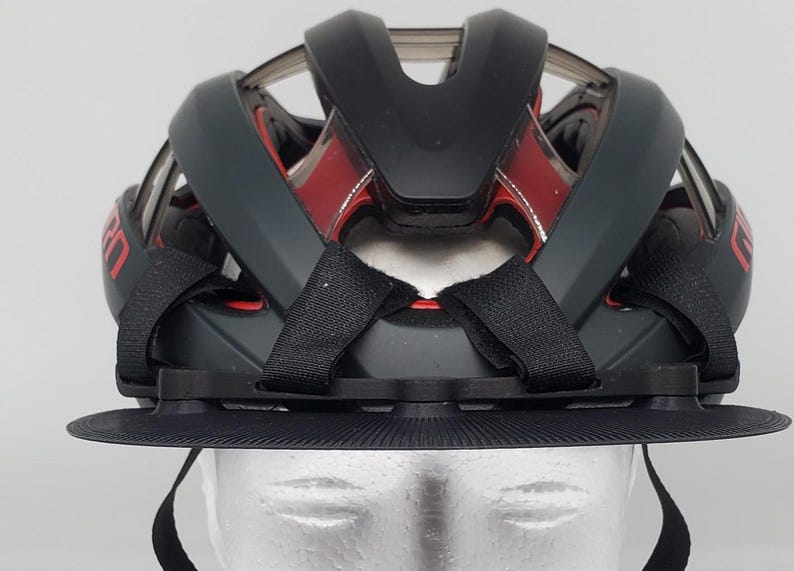 May include: Black bicycle helmet with a red and black design and a black visor. The helmet has adjustable straps and a chin strap.