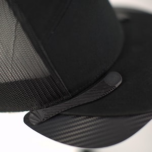 May include: A black mesh and solid fabric baseball cap with a carbon fibre visor.