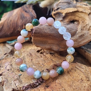 Puede incluir: Un brazalete hecho de varias piedras semipreciosas, incluyendo cuentas rosas, transparentes, marrones y verdes.