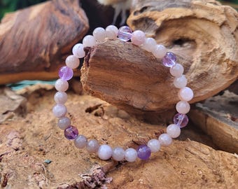 May include: A bracelet made of light pink and gray gemstone beads with purple amethyst beads interspersed throughout.