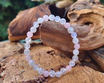 May include: A bracelet made of clear and pink crystal beads. The beads are faceted and have a textured surface.