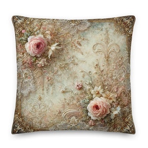 Puede incluir: Una almohada decorativa con un diseño de inspiración vintage con rosas rosas, intrincados adornos dorados y delicados patrones de encaje sobre un fondo azul claro.
