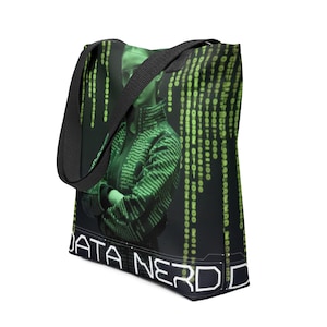 Puede incluir: Bolso tote negro con una imagen teñida de verde de una persona con los brazos cruzados, sobre un fondo de código binario verde. Las palabras "DATA NERD" se muestran en blanco, delineadas en una fuente de estilo neón.