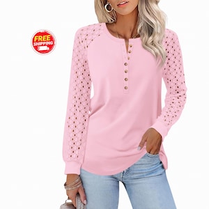 May include: A light pink long-sleeve shirt with a round neckline and a button-down placket. The sleeves have a unique openwork design. The shirt is paired with blue jeans. A "FREE SHIPPING" logo is visible.